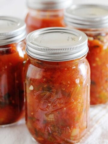 image: Four full jars of canned red salsa