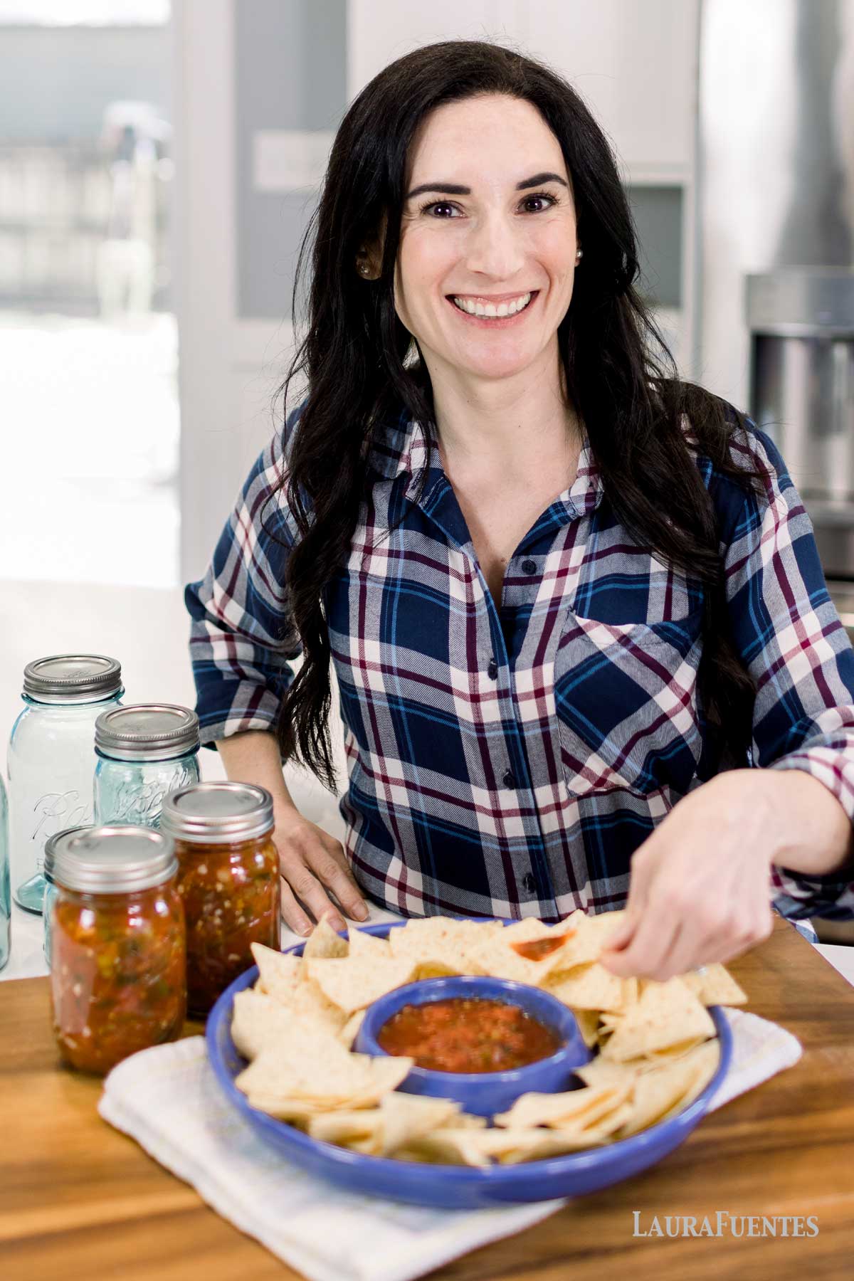 Woman with a dish full of corn chips and cans of salsa