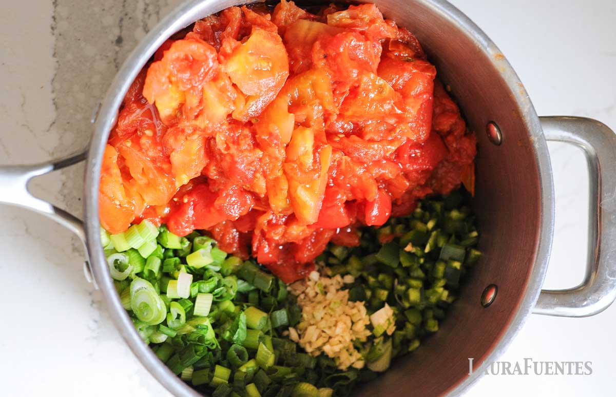image: freshly crushed tomatoes, green onions, seasoning and diced jalepeno in a saucepan
