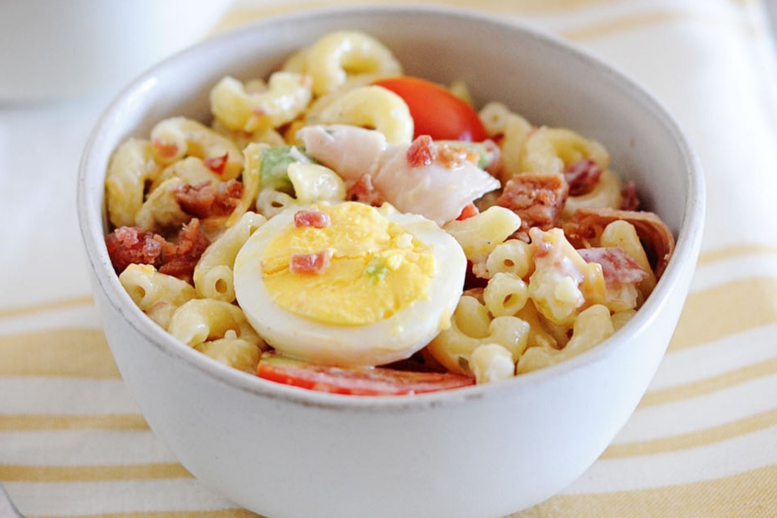 a bowl of cobb pasta salad with a hard boiled egg on top