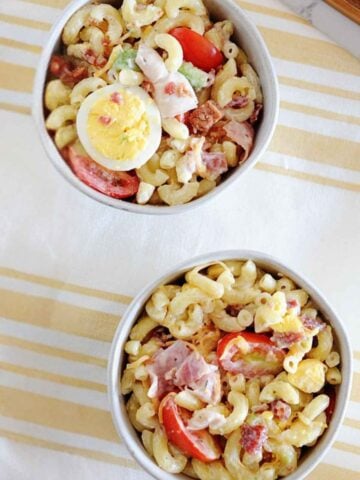 two bowls of cobb pasta salad with a hard boiled egg on top