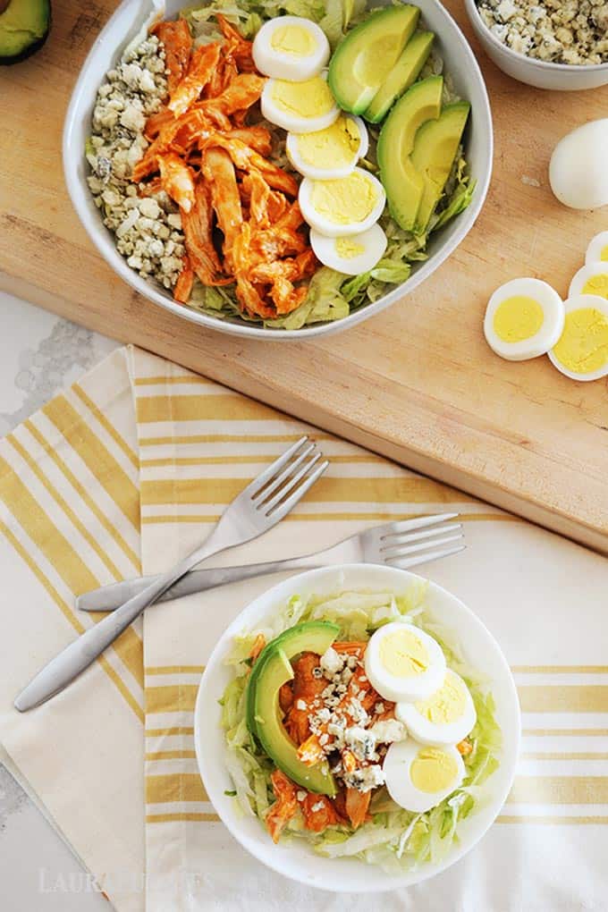 image: Large serving bowl of buffalo chicken salad with smaller bowl of the salad and two forks