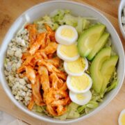 a bowl of buffalo chicken salad with hard boiled egg and avocado