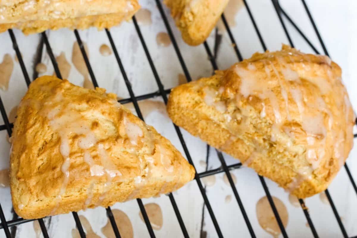 two paleo scones with glaze on a cooling rack