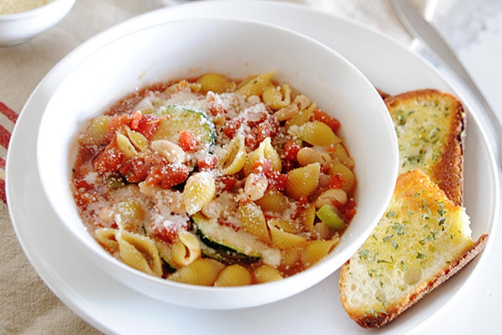 a bowl of vegetarian minestrone with slices of toasted bread on the side