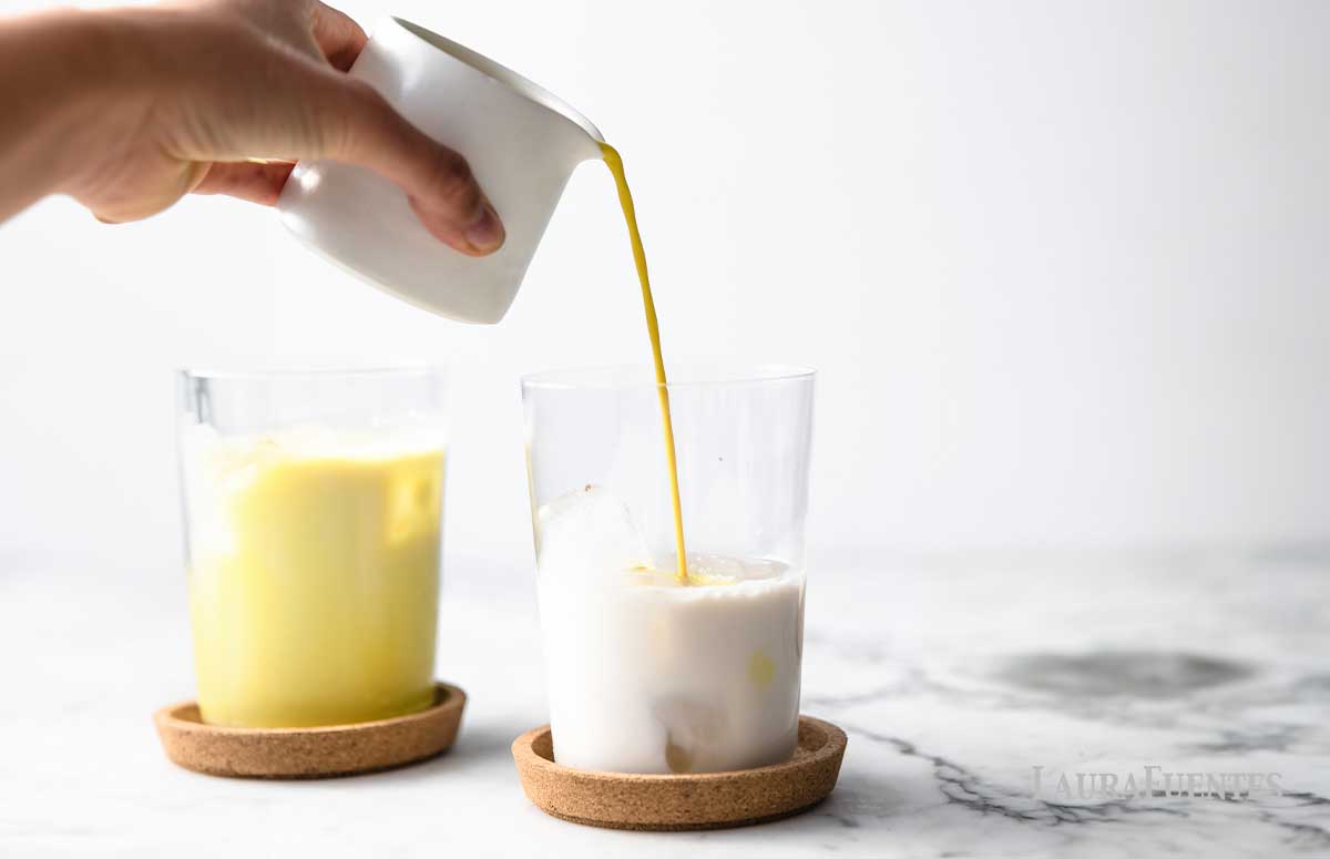 Pouring tumeric mixture into glass of ice milk