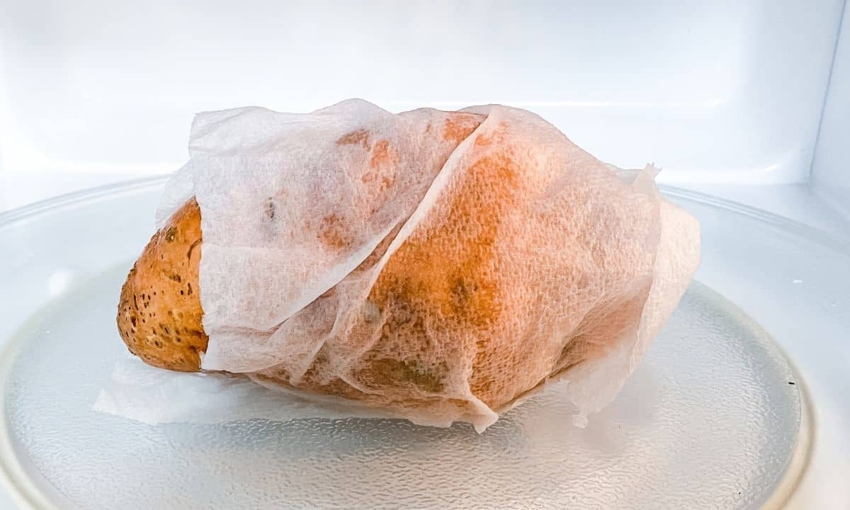 a sweet potato wrapped with paper towel in the microwave