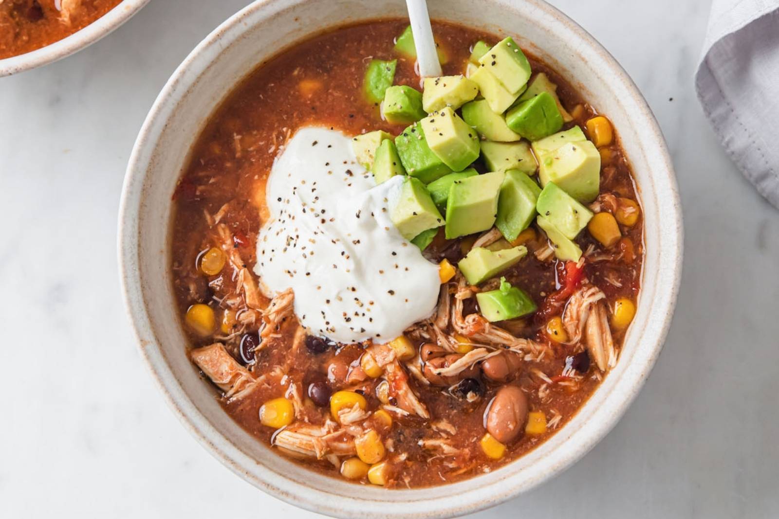 top view of a chicken taco soup topped sour cream and avocado