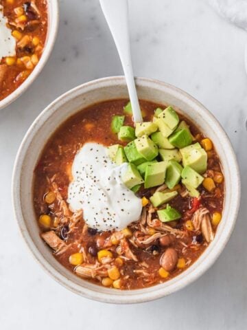top view of a chicken taco soup topped sour cream and avocado
