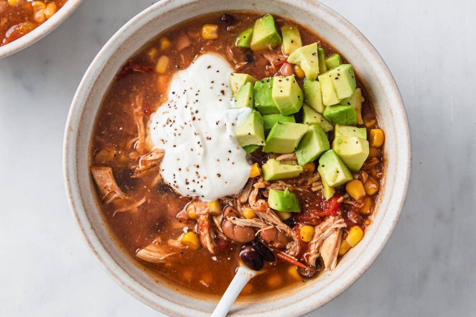 top view of a turkey taco soup topped sour cream and avocado