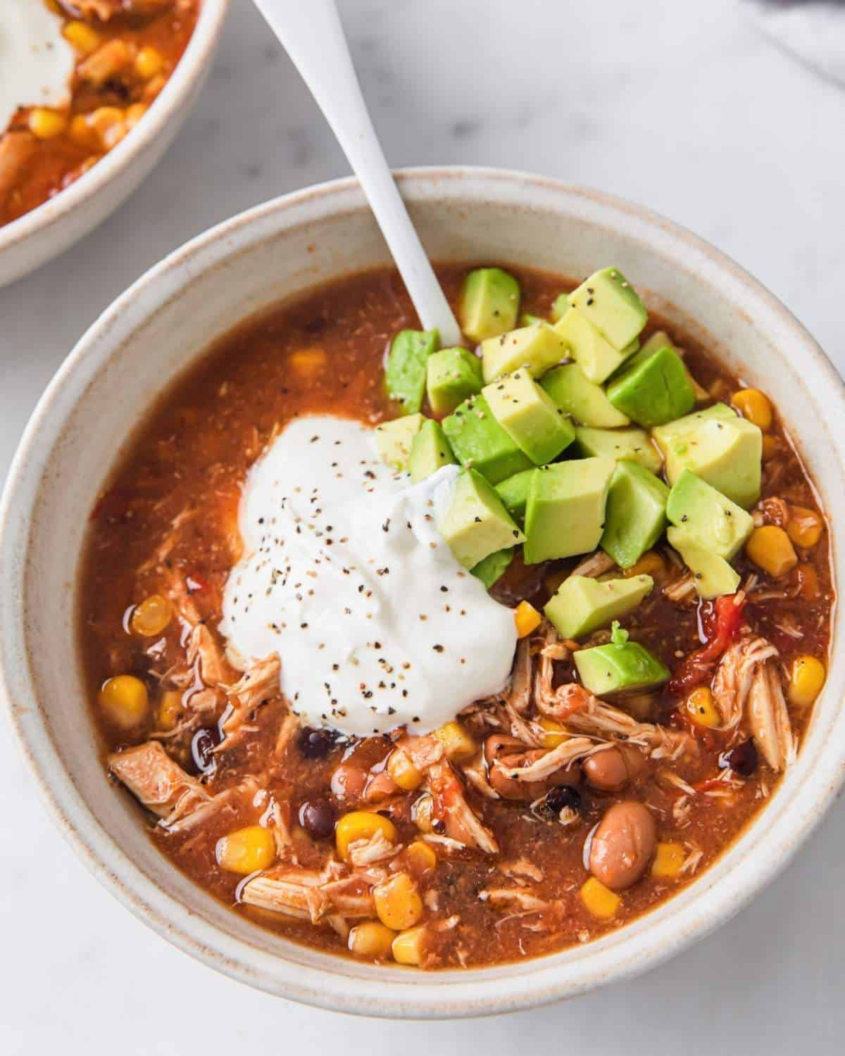 top view of a turkey taco soup topped sour cream and avocado