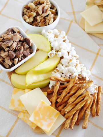 apple slices, popcorn, cheese and pretzel sticks on a platter