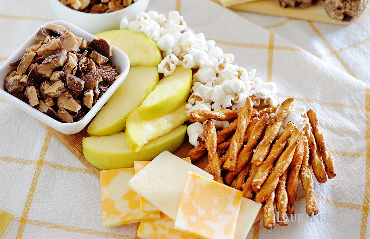 apple slices, popcorn, cheese and pretzel sticks on a platter
