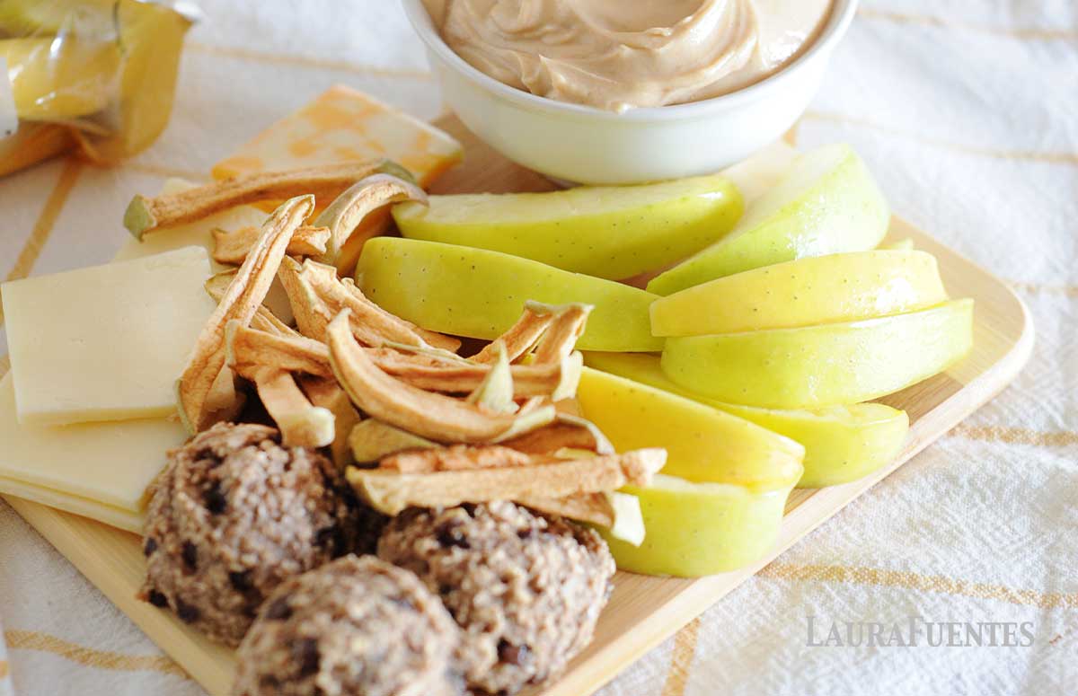 apple slices, cheese, energy balls, dried apple sticks on a platter, next to a bowl with caramel dip