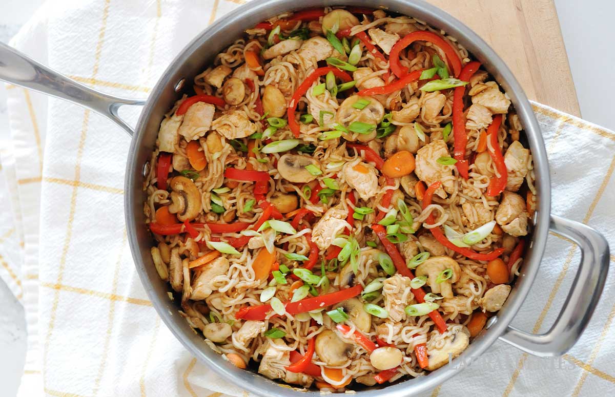sliced mushrooms, red pepper and chicken in a skillet with thin ramen noodles