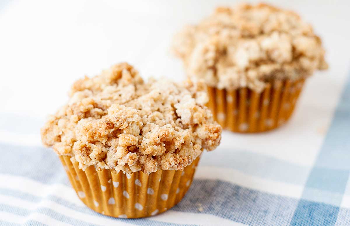 two cinnamon coffee cake muffins with crumb topping