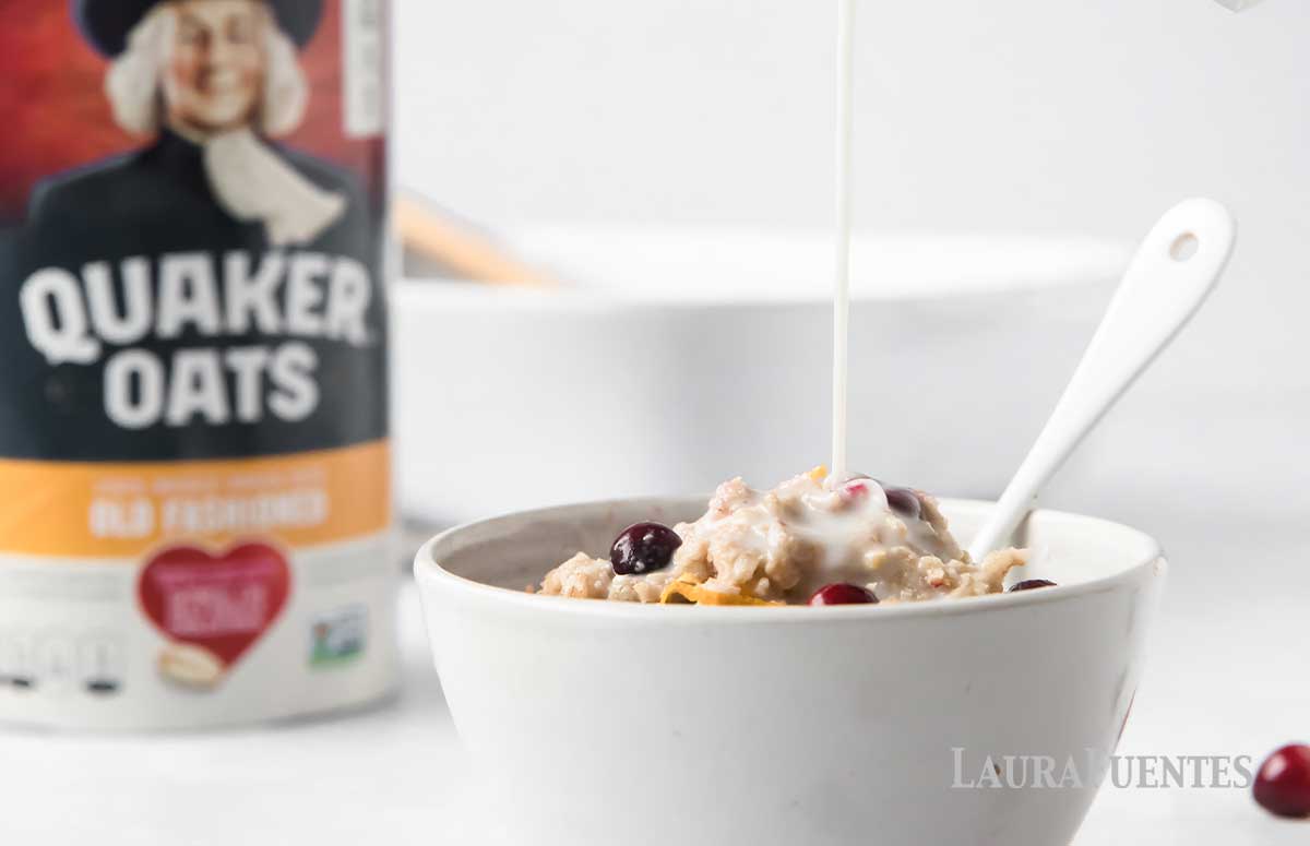 fresh milk being poured into a bowl of baked oatmeal. Cranberries scattered across table