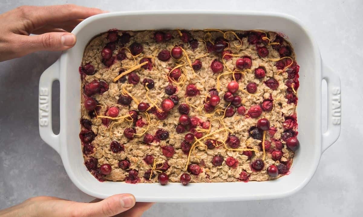 hands showing a baking dish with cranberry baked oatmeal