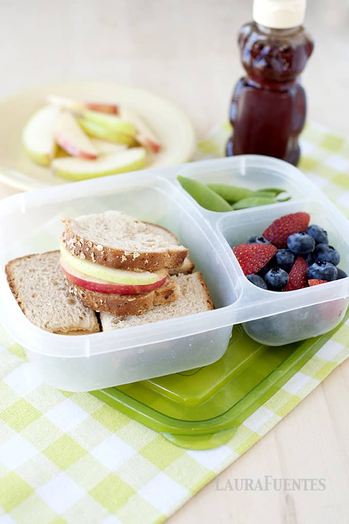 image: lunch container with apple sandwiches, snap peas and fruit