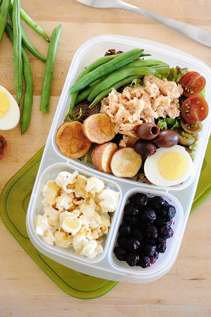 image: lunch container with salmon salad, popcorn and fruit