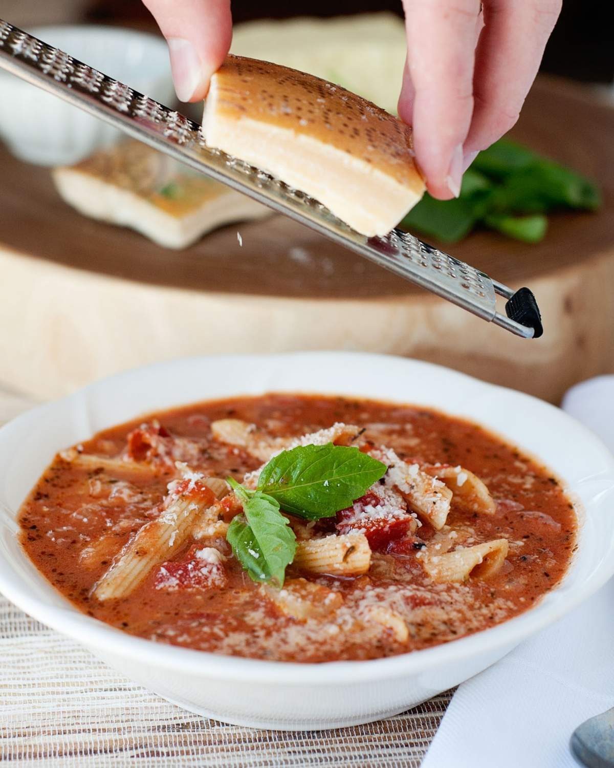 shredding cheese over Parmesan chicken soup