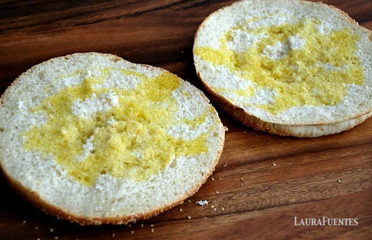 two halves of muffuletta bread topped with olive oil