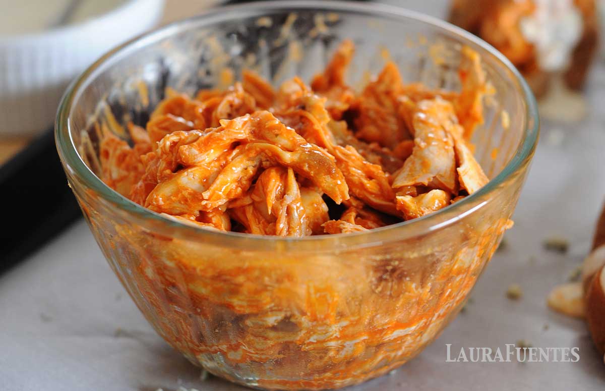 large glass bowl of shredded chicken with buffalo sauce
