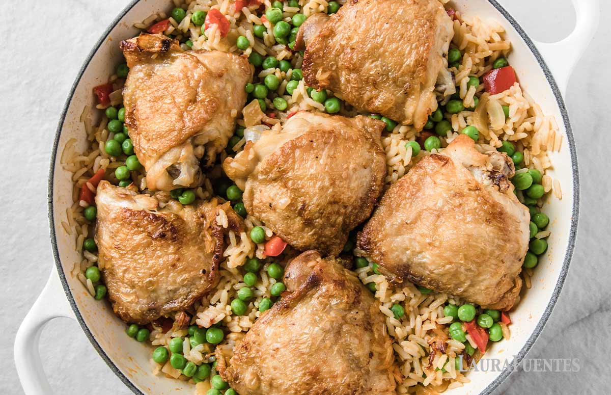 full skillet of rice, peas, peppers and six cooked chicken breasts with crispy skins