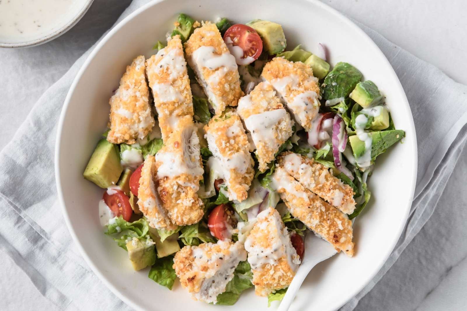 large chicken tender salad in a white bowl