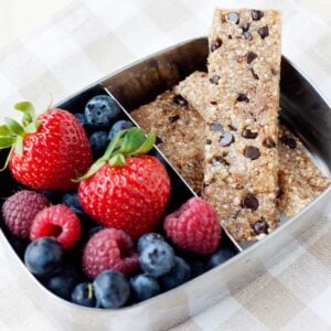 two homemade snack bars in a lunch container with fruit