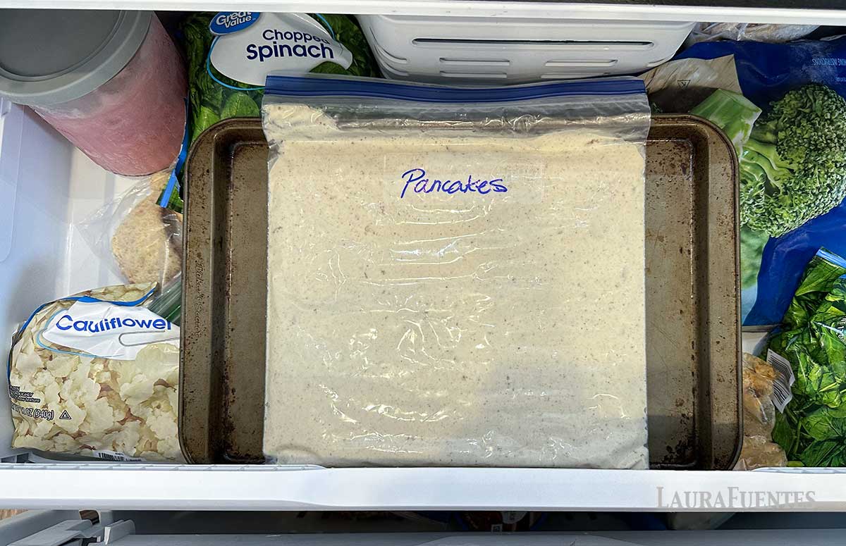frozen pancake batter in a zip bag in the freezer laying on a sheet pan