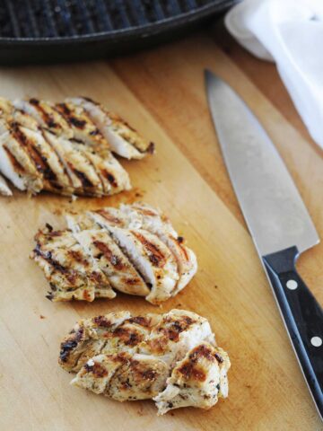 image: three sliced baked chicken breasts on a plate.