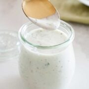 jar of homemade ranch dressing with a spoon in it.