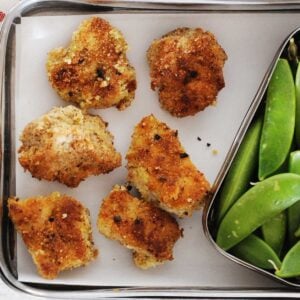 lunchbox with six chicken nuggets and veggies on the side.