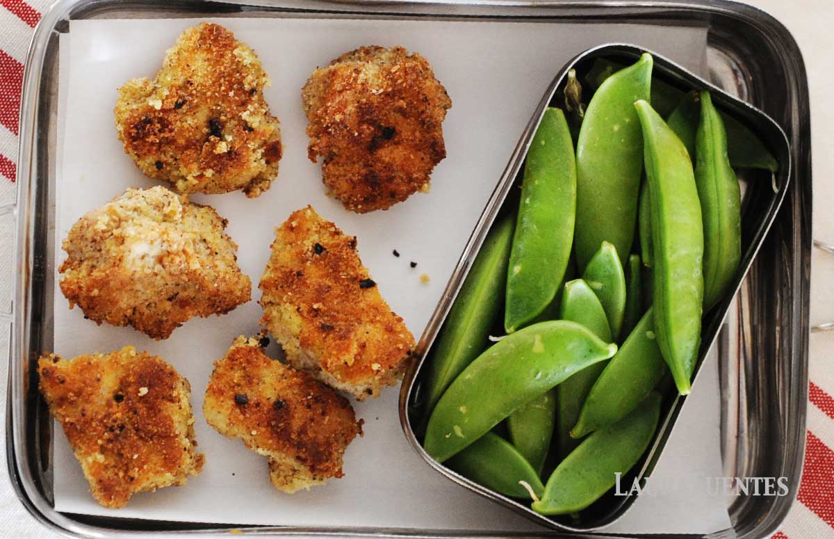 lunchbox with six chicken nuggets and veggies on the side.