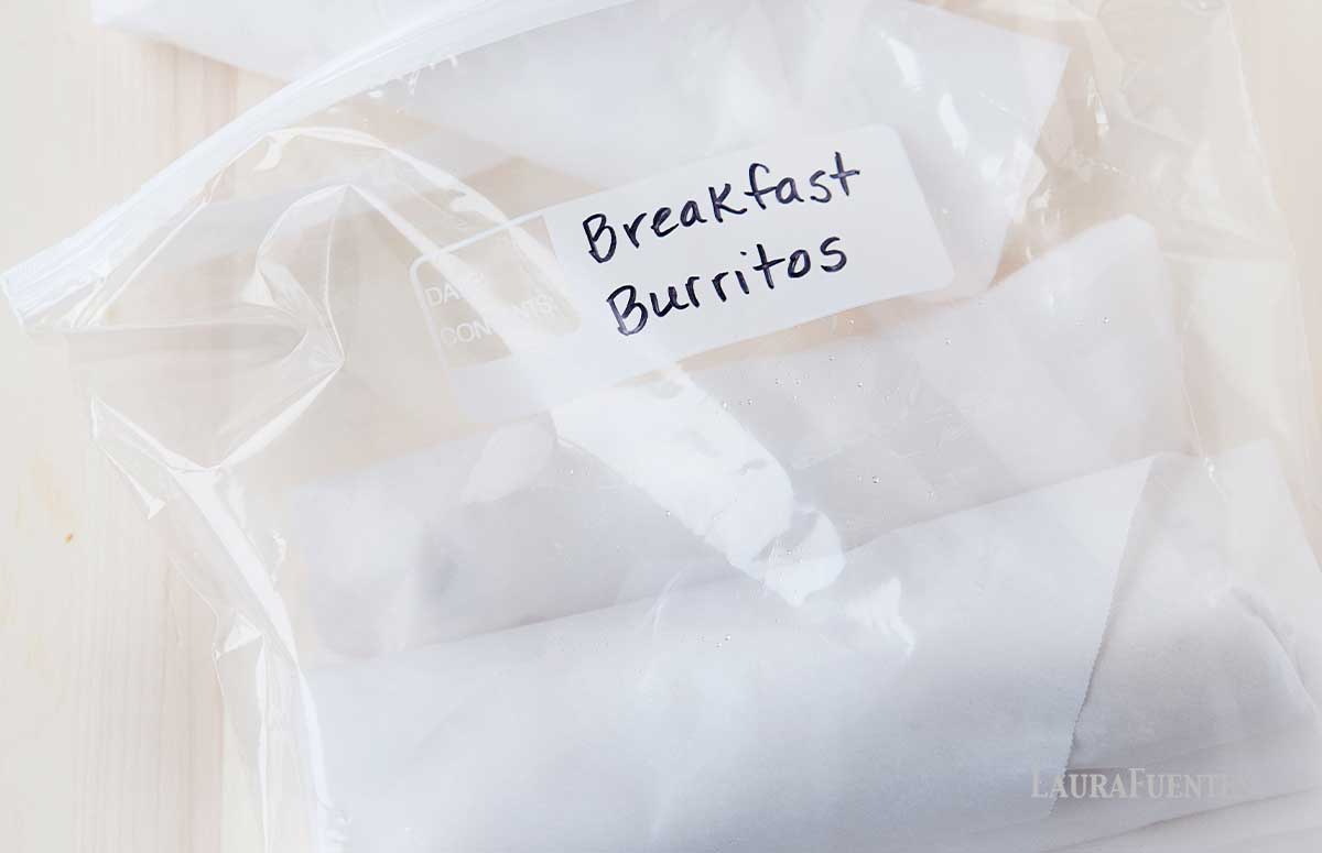 a zip bag with two frozen burritos wrapped in parchment paper