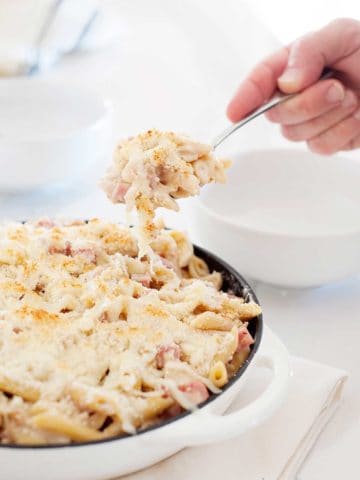 hand pulling a spoonful of chicken cordon bleu casserole from pan