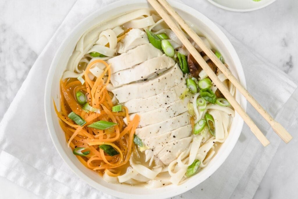 top view of chicken udon soup in a bowl with chopsticks
