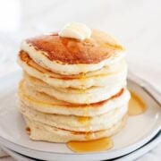 stack of pancakes made without milk on a plate topped with syrup and a pat of butter.