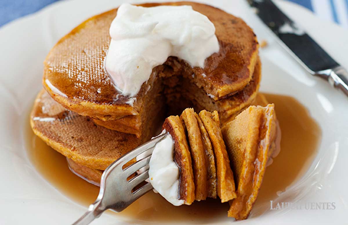 stack of gluten free pumpkin pancakes with triangle shape bite taken out on a fork.