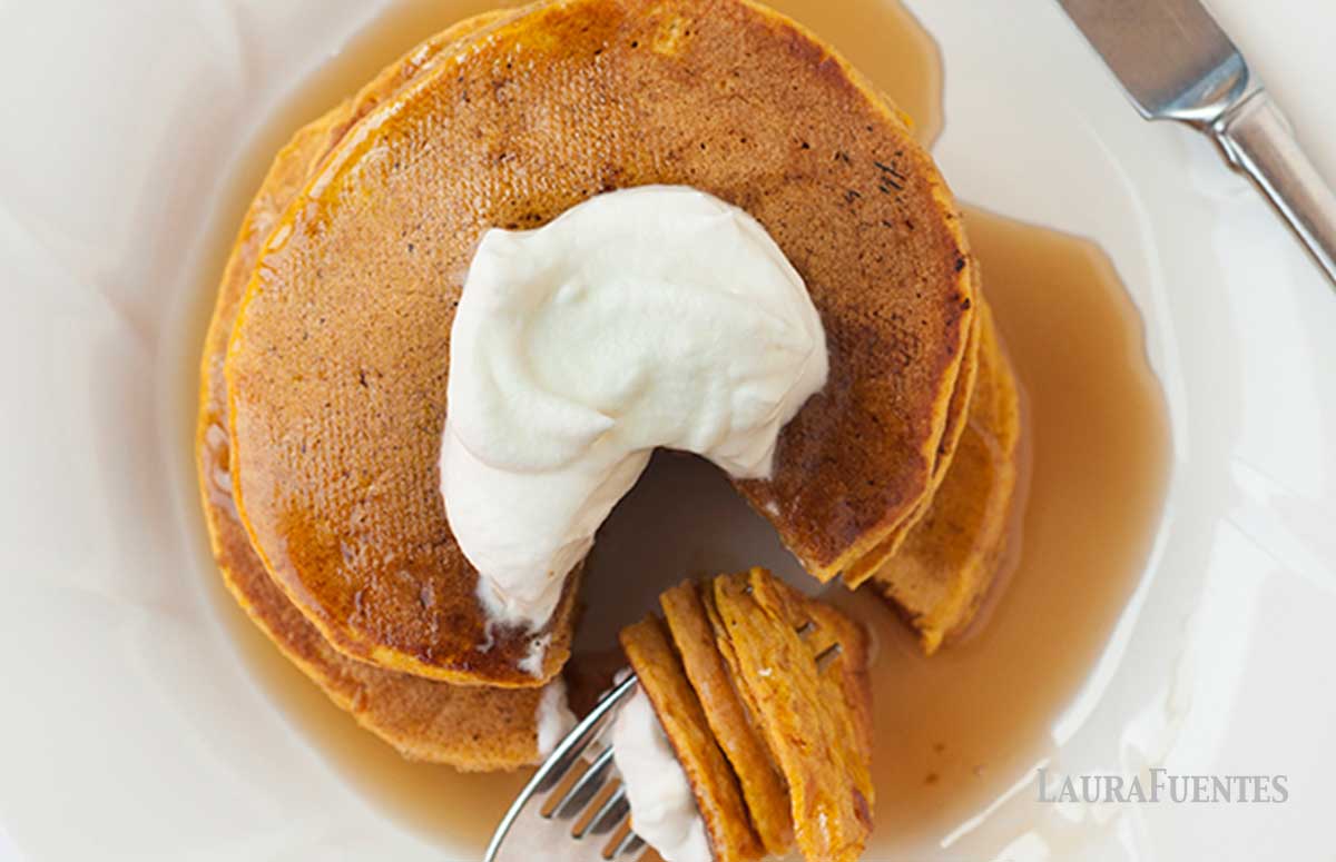 overhead view of gluten free pumpkin pancakes pancake stack topped with whipped cream and syrup