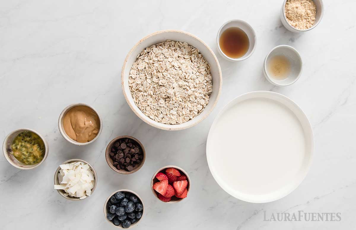 small bowls of ingredients for strawberry overnight oats lined up diagonally on a countertop