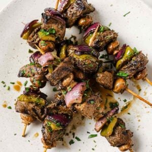 overhead view of delicious marinated grilled beef kabobs on a plate. Beef skewers also have onions and mushrooms