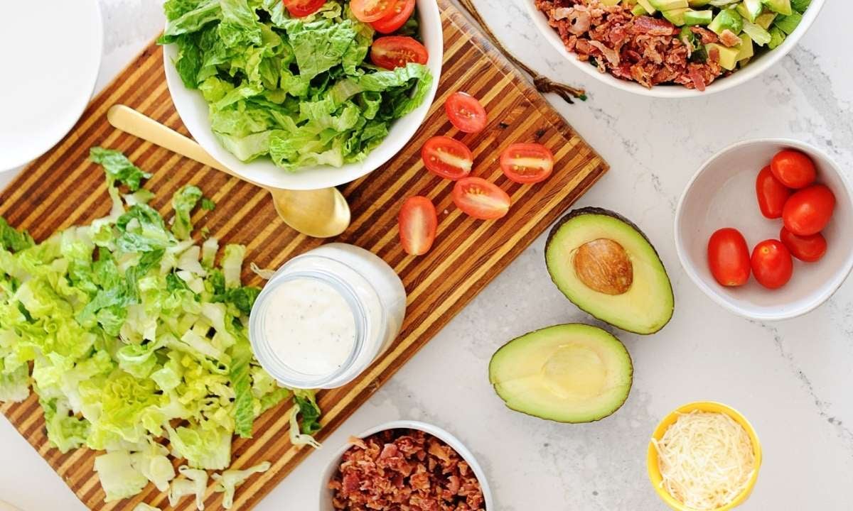 ingredients to make BLT salad: lettuce, bacon, tomato, avocado, dressing and cheese