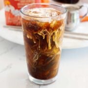 iced coffee in a glass with cream being mixed in