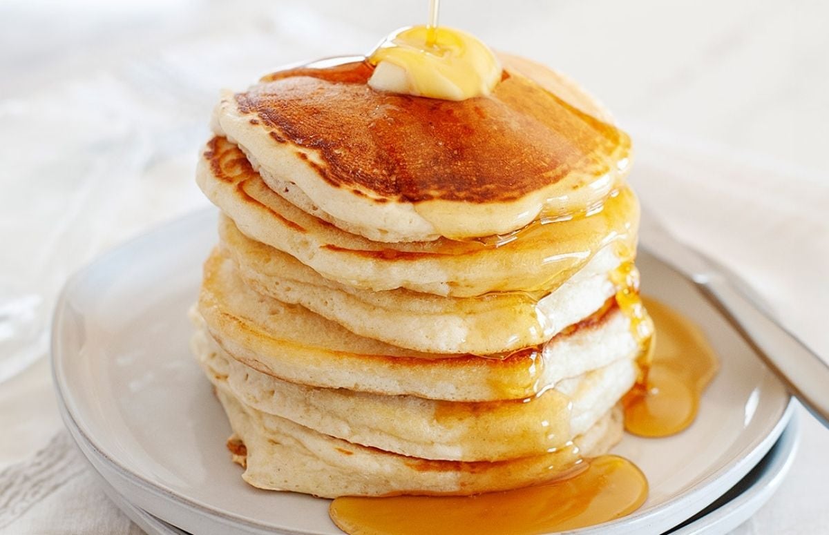 stack of pancakes made without milk on a plate topped with syrup and a pat of butter.