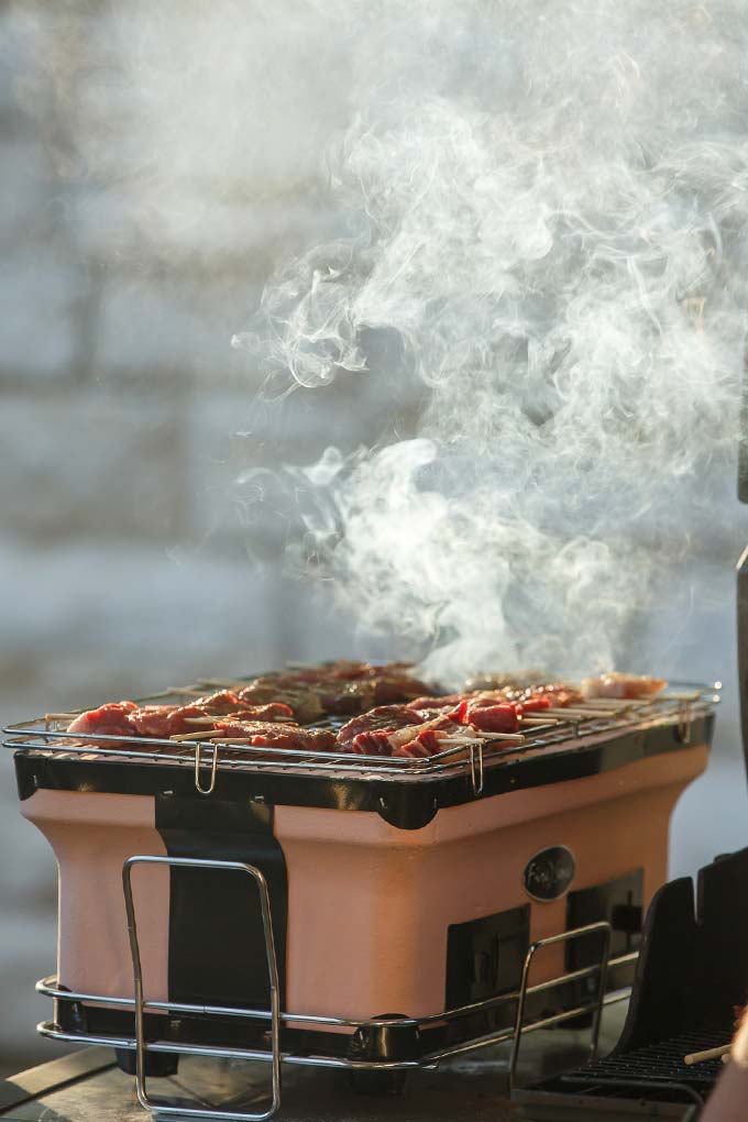 image: beef skewers on a grill with smoke coming off the top