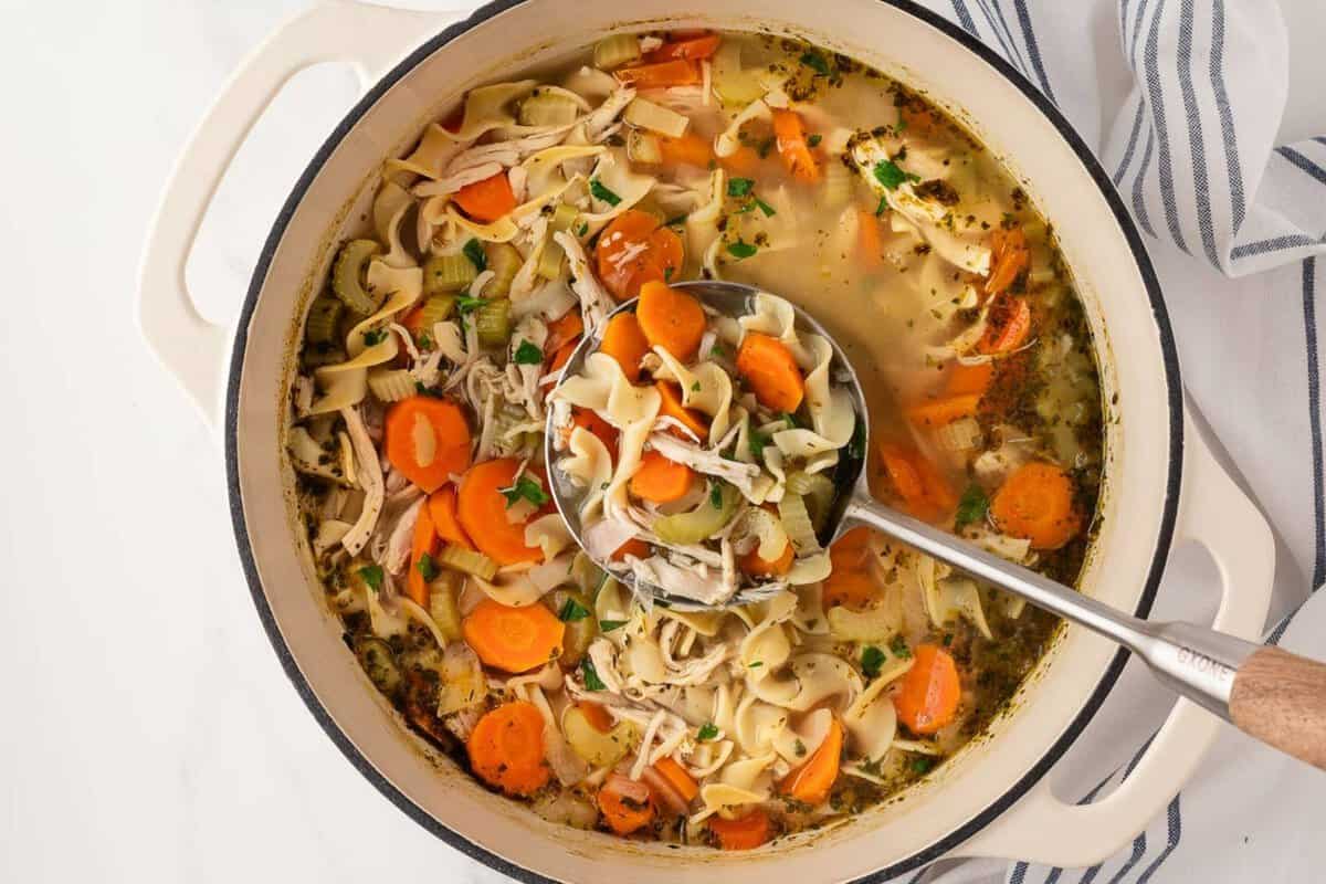 large pot of rotisserie chicken noodle soup with a ladle in it