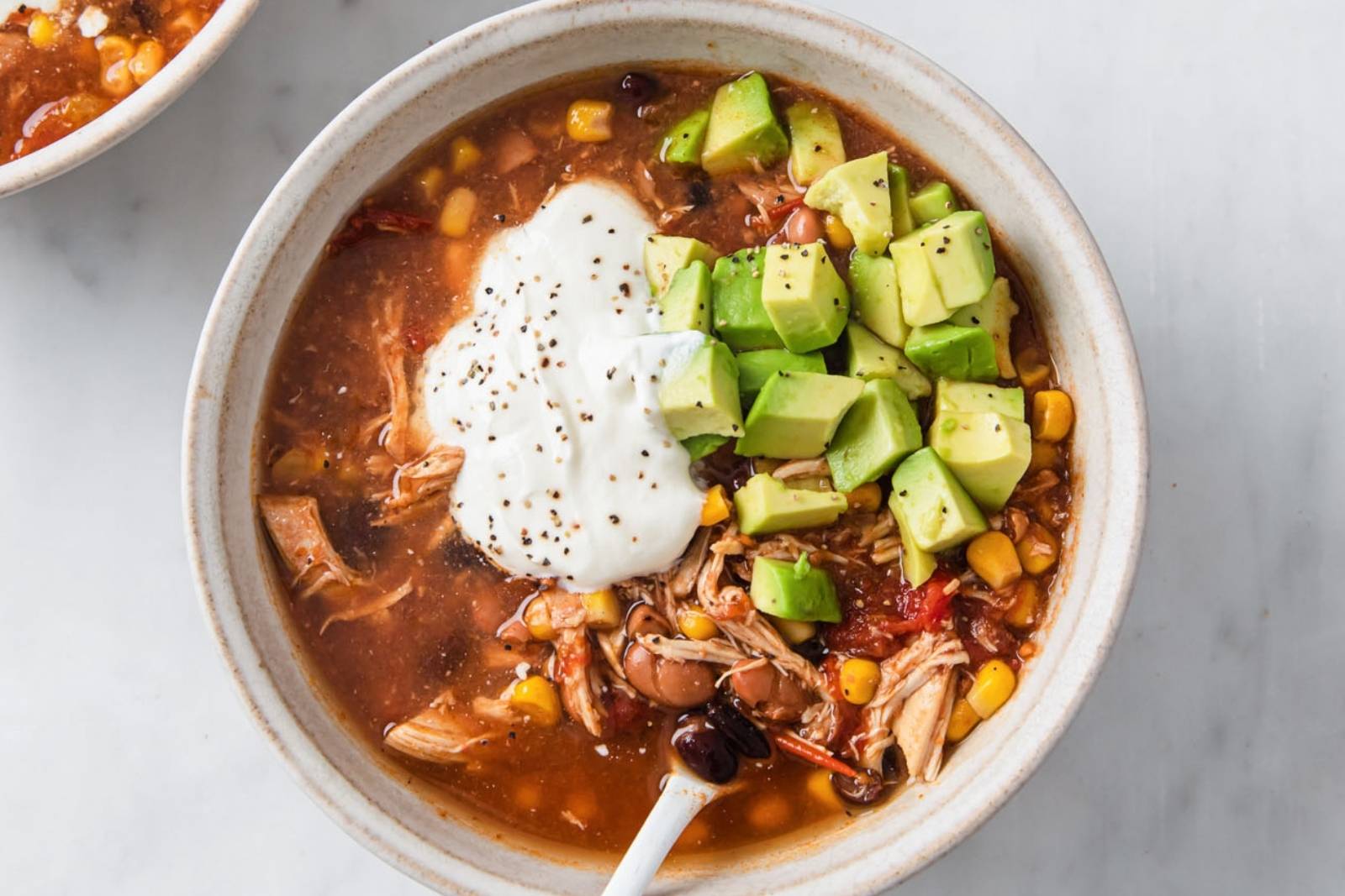 top view of a bowl of chicken taco soup topped with sour cream and avocado