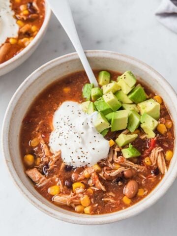 top view of a bowl of chicken taco soup topped with sour cream and avocado